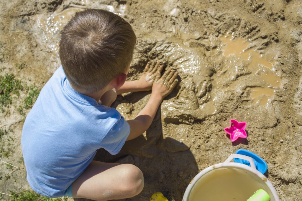 Kid is playing with wet sand on summer holidays-Cyboard School