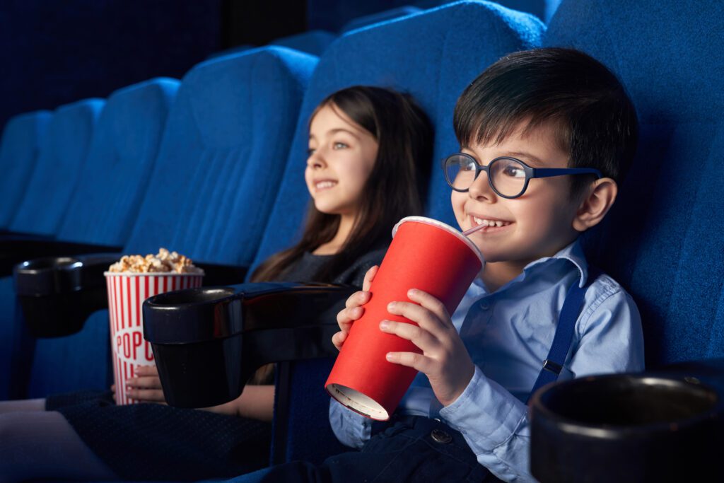 Two kids are enjoying their movie night with popcorn and soft drink-Cyboard School