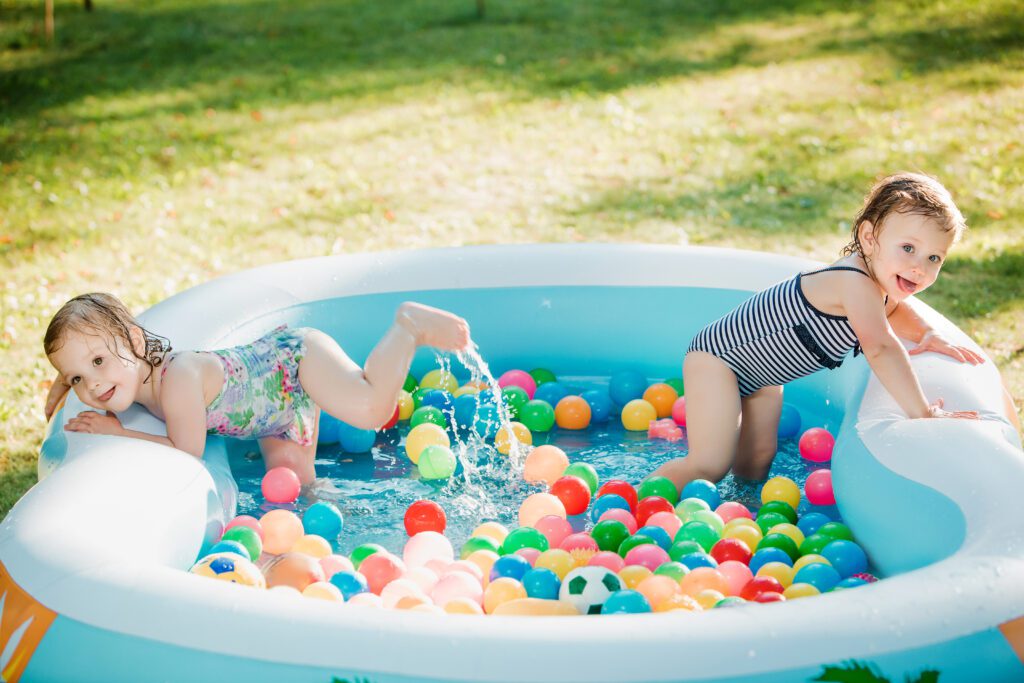 The two little baby girls playing with toys in a pool in the summer sunny day-Cyboard School