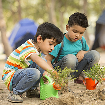 Two Kids planting a sapling together in a park